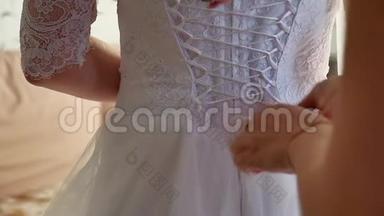 新娘穿上婚纱。 帮新娘穿上婚纱。 新娘穿上婚纱结婚的概念